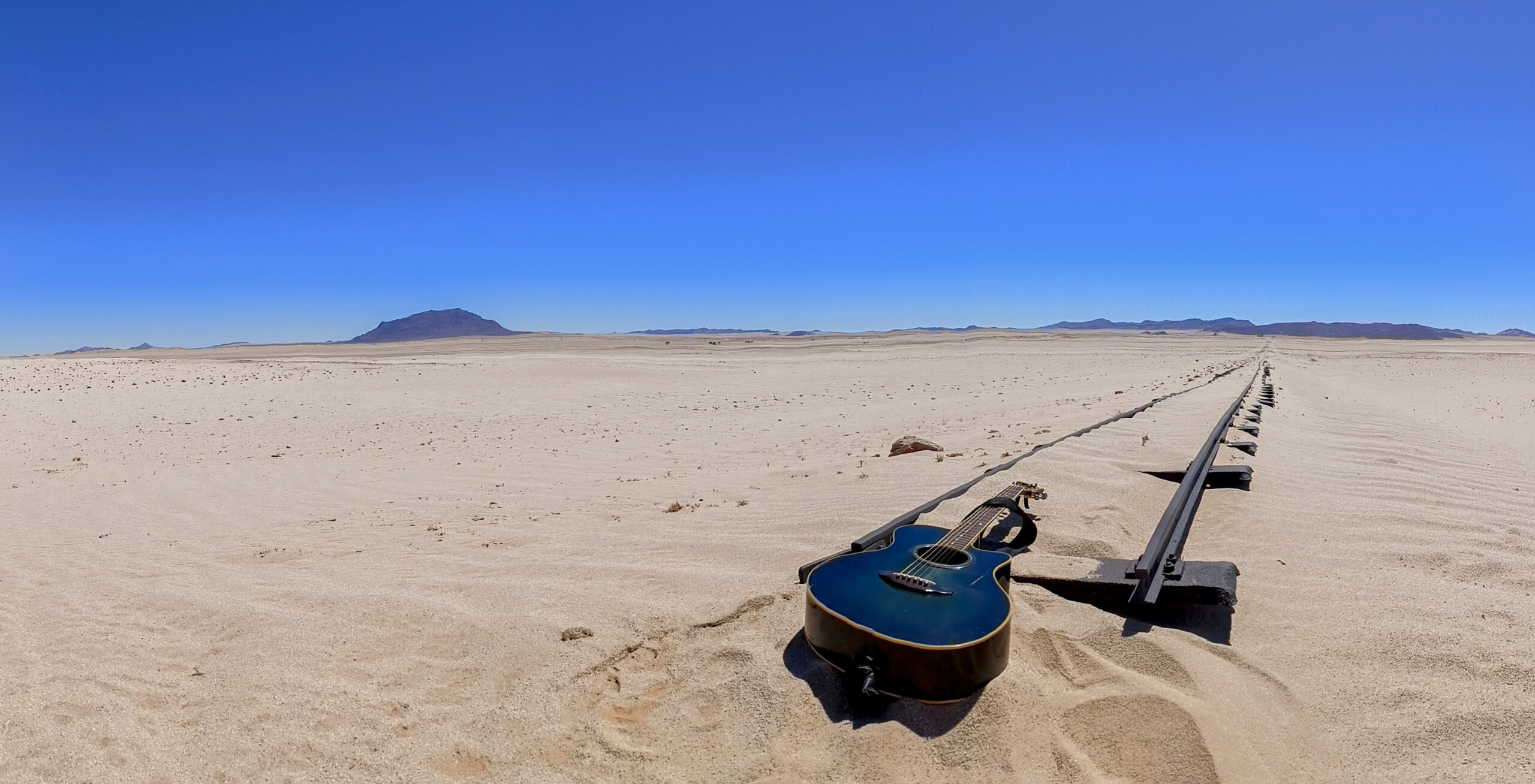 Guitar on desert floor at end of old railway tracks